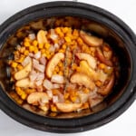 A crock pot filled with apples and carrots.