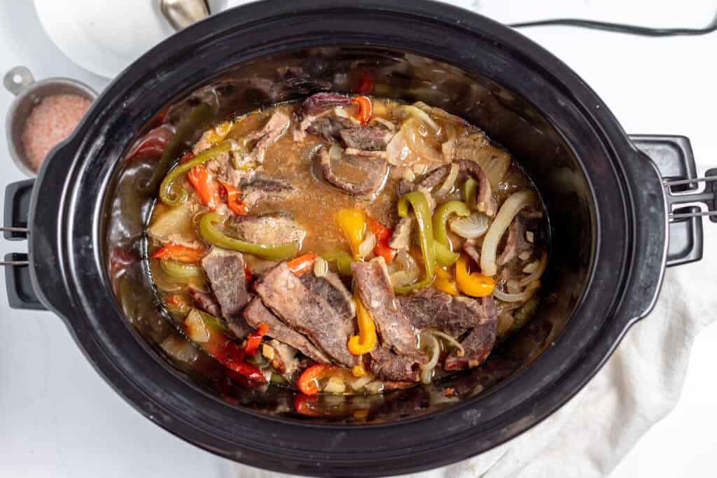 A crock pot full of meat and vegetables.