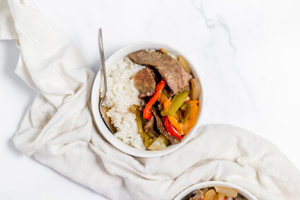 A bowl of beef stir fry with peppers and rice.