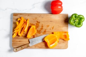 Sliced peppers on a cutting board with a knife.