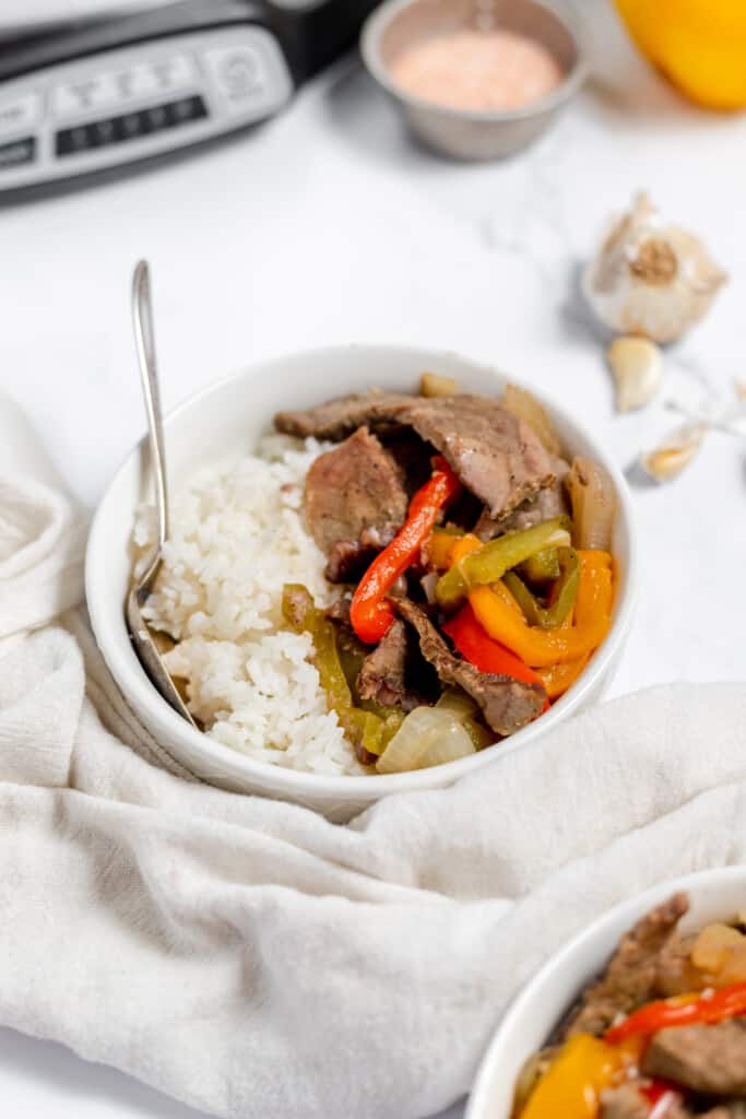 A bowl of rice with beef and peppers in it.