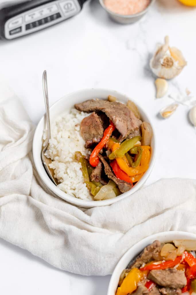 A bowl of rice with beef and peppers in it.