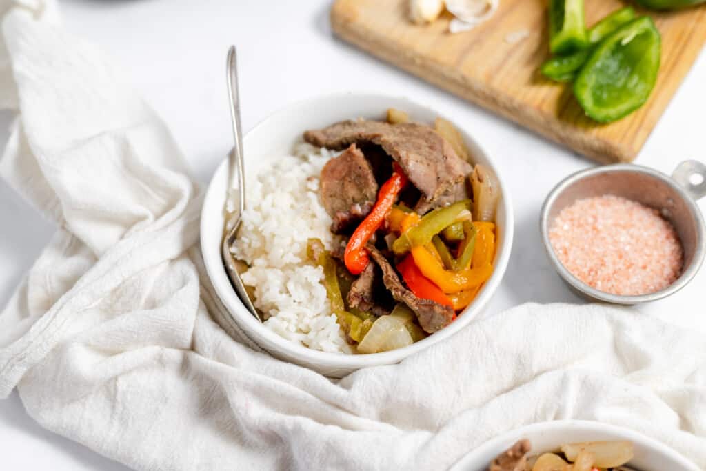 A bowl of beef stir fry with peppers and rice.