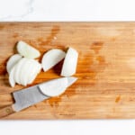 Sliced onions on a cutting board with a knife.