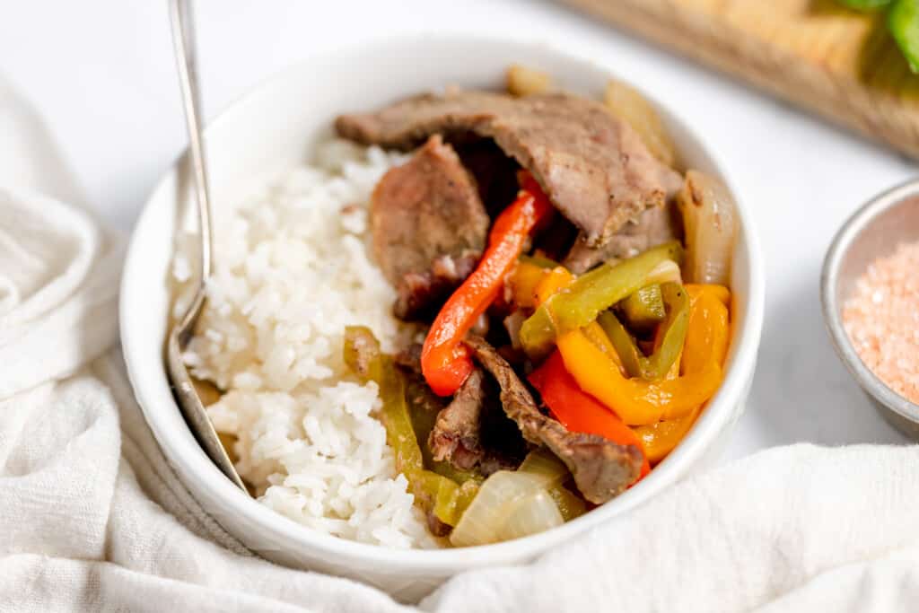A bowl of beef stir fry with peppers and rice.