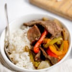 A bowl of rice with beef and peppers in it.