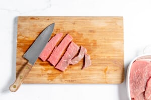 Sliced beef on a cutting board next to a knife.