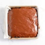 A chocolate cake in a baking pan on a marble countertop.
