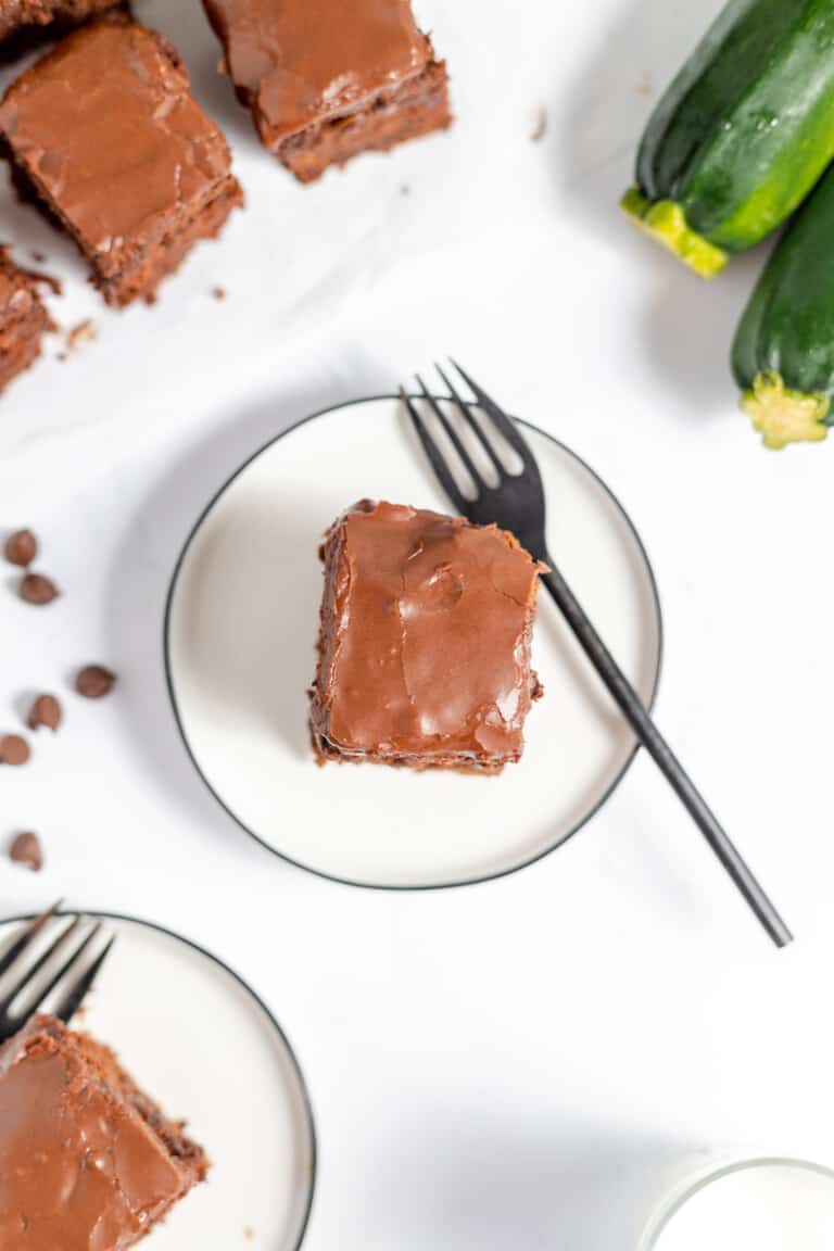 Chocolate brownies on a white plate with a knife and fork.