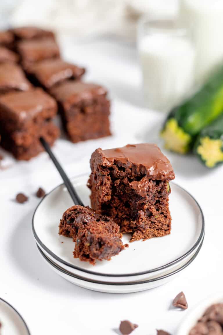 Chocolate brownies on a white plate with a knife and fork.