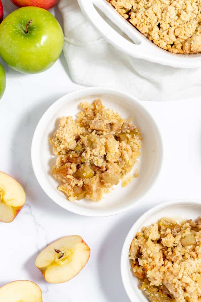 Three bowls of apple crumble with apples in them.