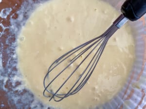 A bowl of chocolate fudge cake batter with a whisk in it.