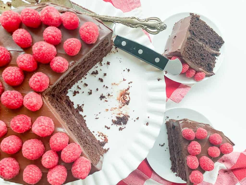A decadent chocolate fudge cake with raspberries on a plate.