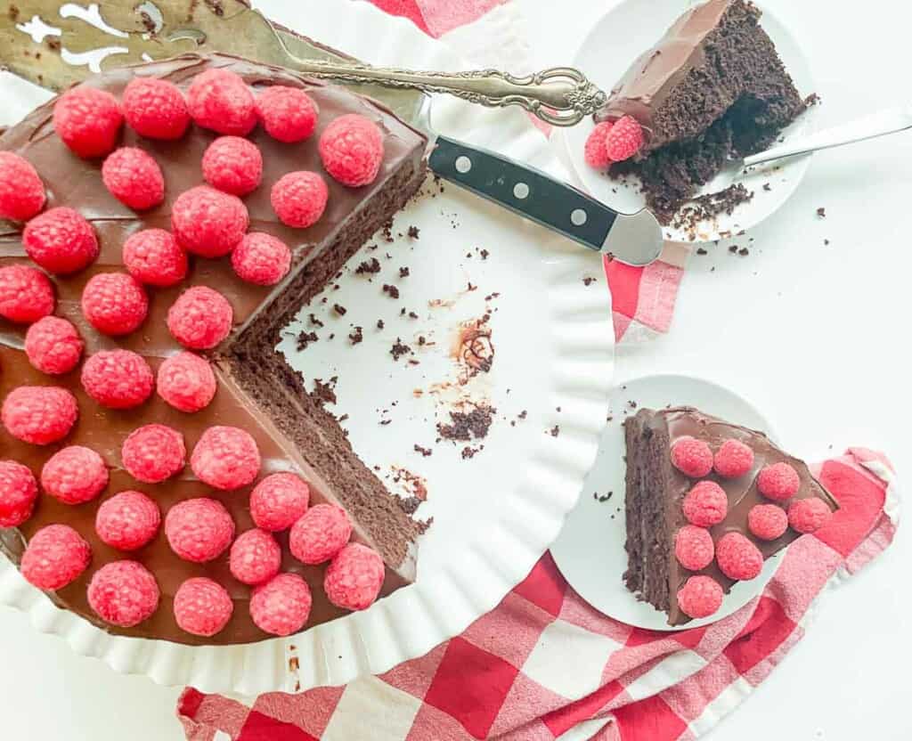 A chocolate fudge cake with raspberries on a plate.