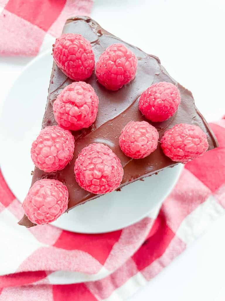 A slice of chocolate fudge cake with raspberries on top.