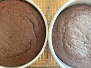 Two chocolate fudge cakes on a cooling rack.