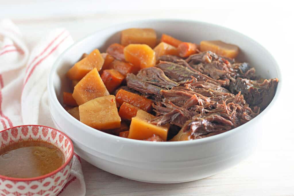 A bowl of pot roast with carrots and potatoes.