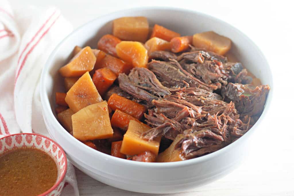 A bowl of slow cooker roast with carrots and potatoes.