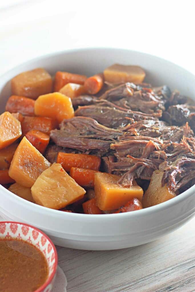 A bowl of beef with carrots and potatoes.