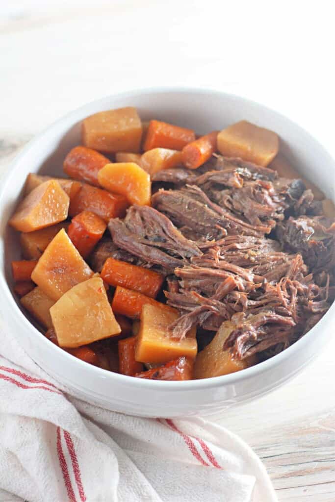 A bowl of beef roast with carrots and potatoes.