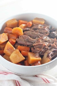 A bowl of roast beef with carrots and potatoes.