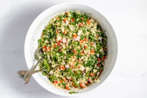 Quinoa salad in a white bowl with a spoon.