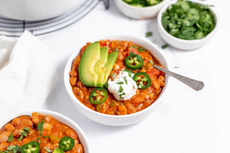 Two bowls of turkey pumpkin chili with sour cream and avocado.