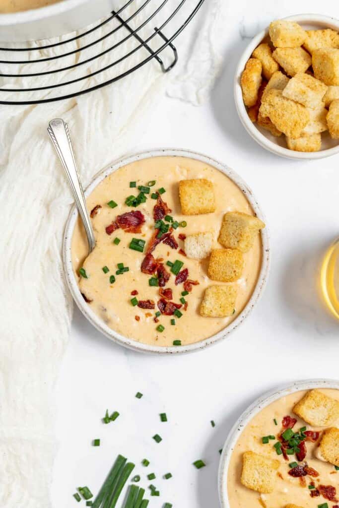 A bowl of cheese soup with bacon and croutons.