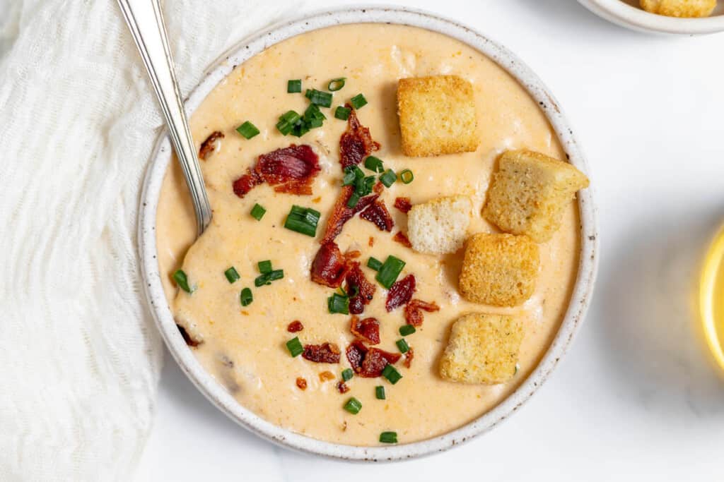 A bowl of cheese soup with bacon and croutons.