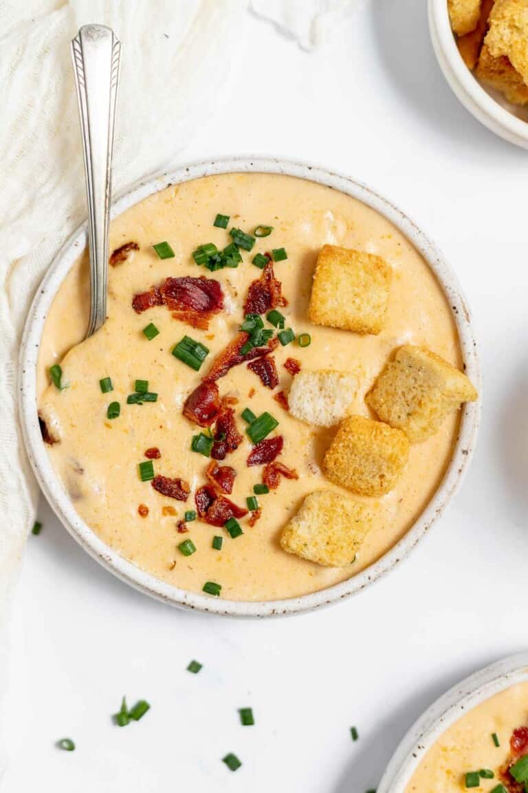 A bowl of cheese soup with bacon and croutons.