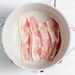 Bacon in a pan on a marble countertop.