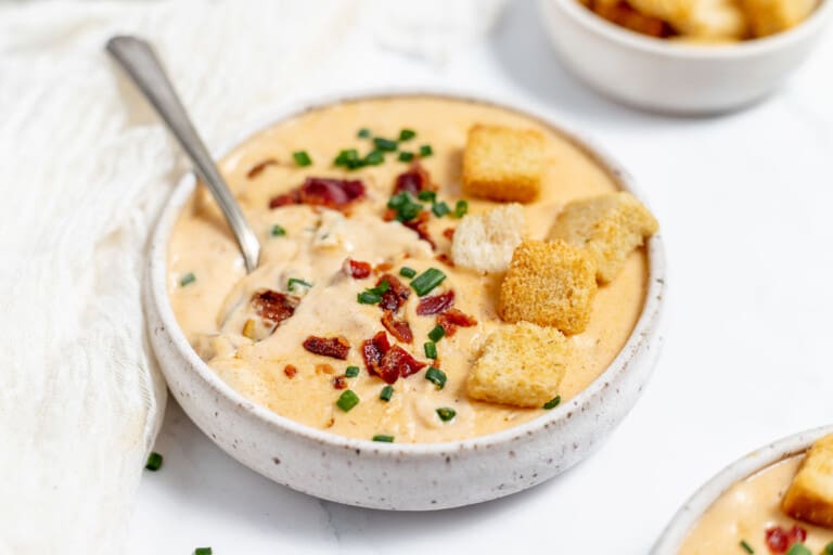 A bowl of soup with bacon and croutons.