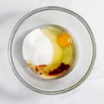 A glass bowl with an egg and sugar in it.