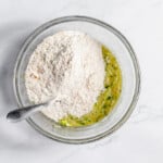 A bowl of flour and a spoon next to it.