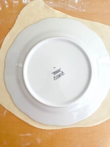 A plate is sitting on top of a piece of dough.