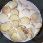A pan with milk and potatoes in it.