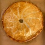A pie is sitting on top of a baking sheet.
