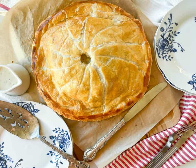 A pie is sitting on a plate next to a fork.