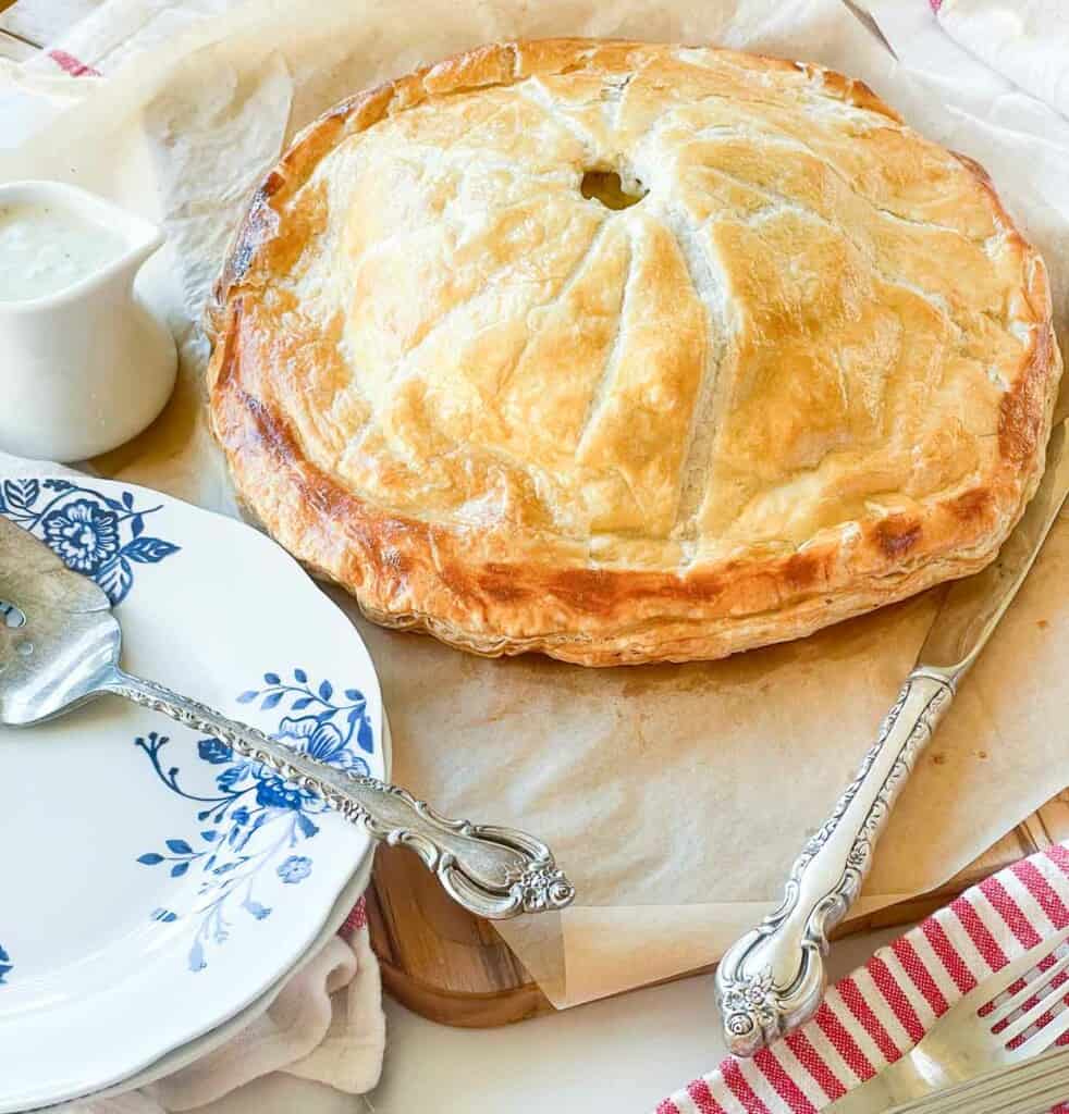 A pie on a plate next to a spoon and fork.