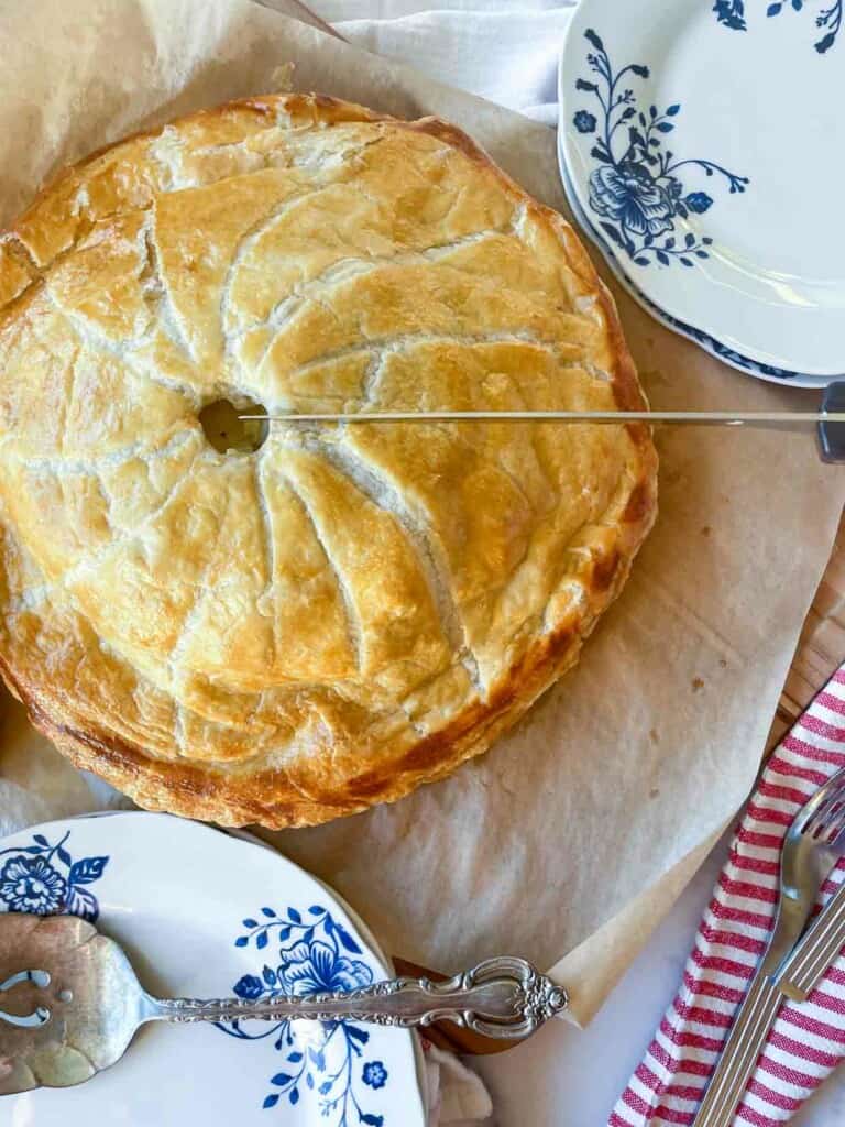 A pie on a plate with a knife and fork.