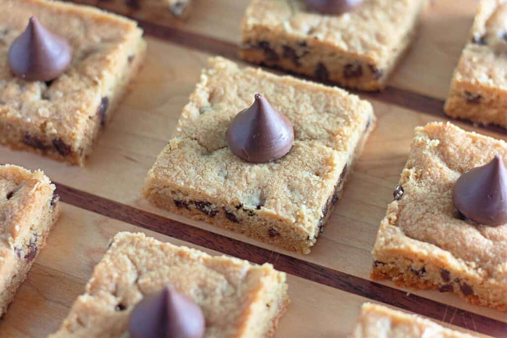 Chocolate chip cookie bars on a wooden cutting board.
