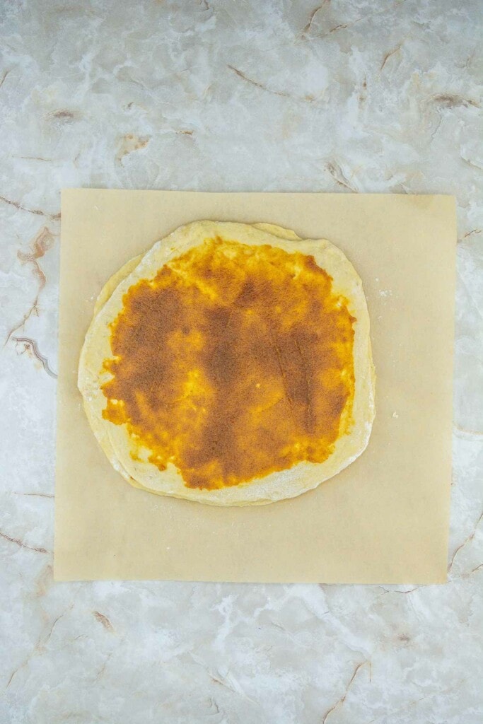 A pizza on a baking sheet with cheese on it.