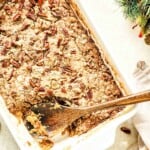 A dish of Sweet Potato Dump Cake with pecans and a wooden spoon.