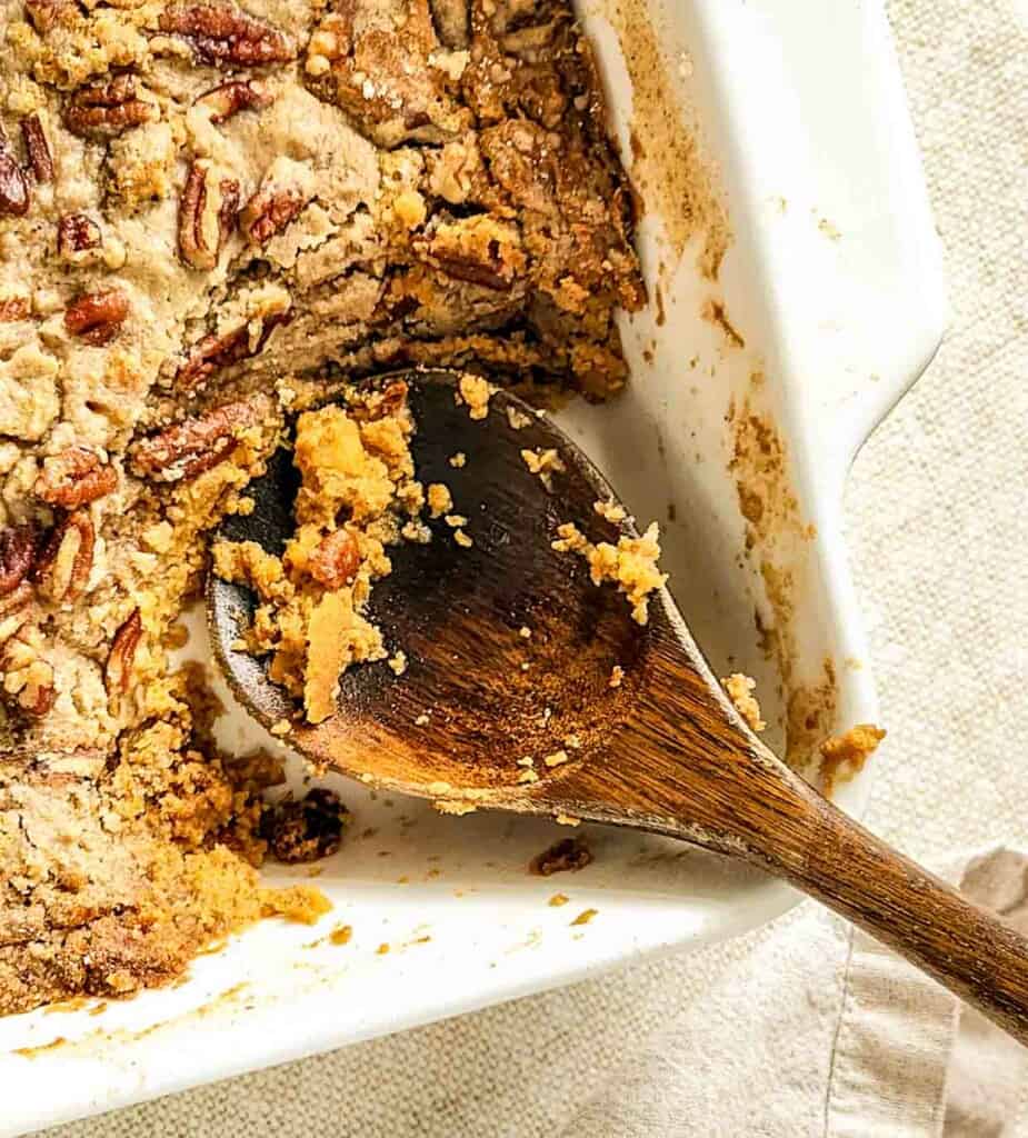 A dish of cake with pecans and a wooden spoon.