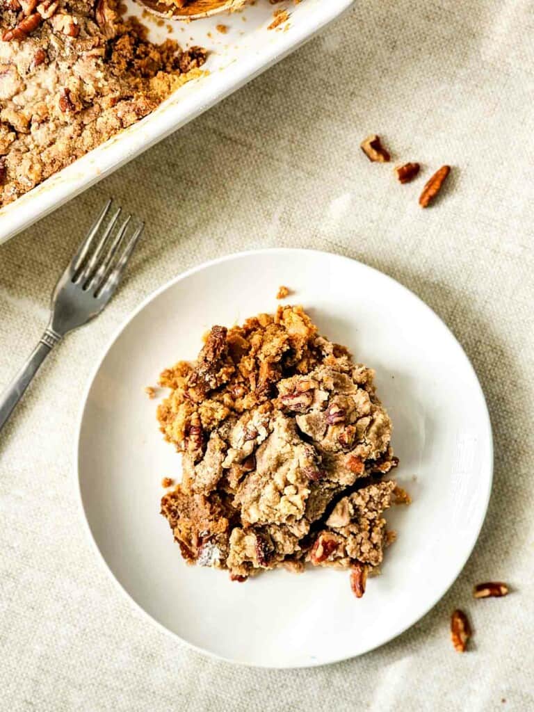A plate of cake with pecans and a fork.