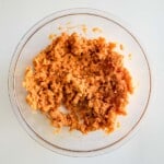 A bowl of mashed potatoes with carrots in it.