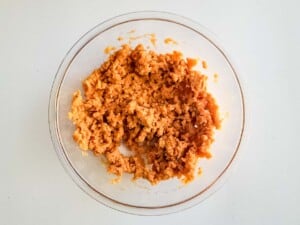 A bowl of mashed potatoes with carrots in it.