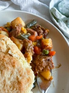 A plate of beef pot pie with biscuits on it.