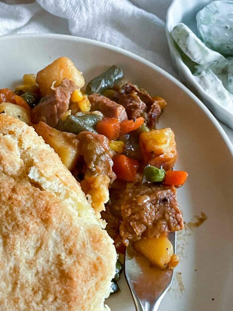 A plate of beef pot pie with biscuits on it.