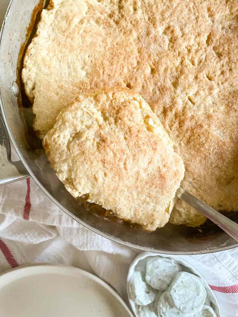 A pan of beef pot pie biscuits with a spoon in it.